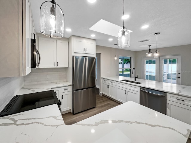 kitchen featuring stainless steel appliances, light stone counters, decorative light fixtures, and sink