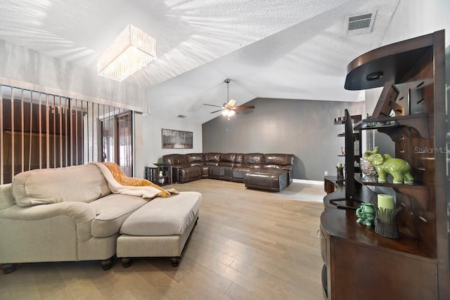 living room featuring ceiling fan, lofted ceiling, a textured ceiling, and wood-type flooring