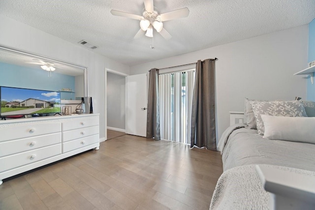 bedroom with a textured ceiling, ceiling fan, and light hardwood / wood-style flooring