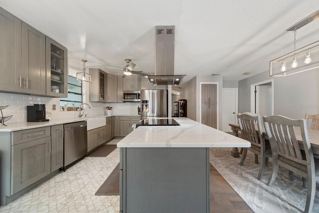 kitchen with island exhaust hood, stainless steel appliances, hanging light fixtures, a center island, and sink