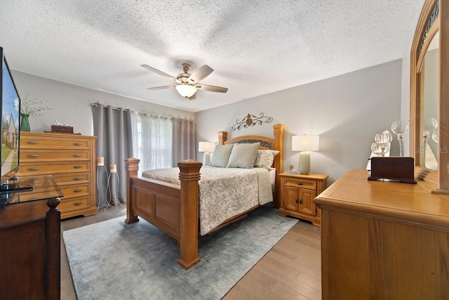 bedroom with ceiling fan, light wood-type flooring, and a textured ceiling