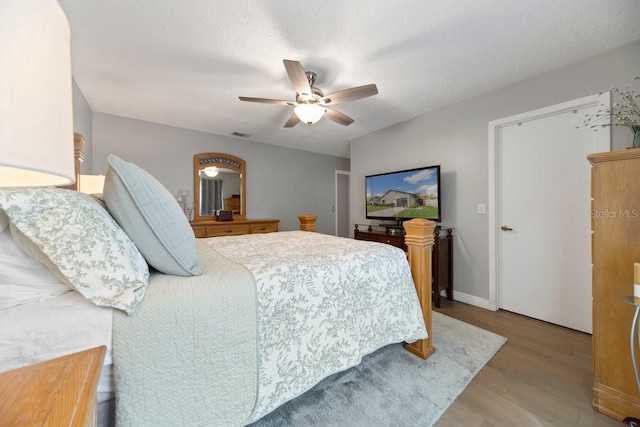 bedroom featuring ceiling fan, light hardwood / wood-style flooring, and a textured ceiling