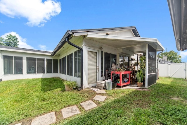 back of property with a yard and a sunroom