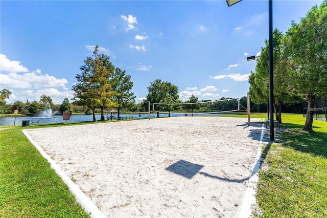 view of community with a lawn, a water view, and volleyball court