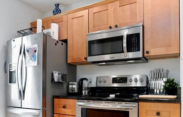 kitchen featuring light brown cabinets, dark stone counters, and appliances with stainless steel finishes