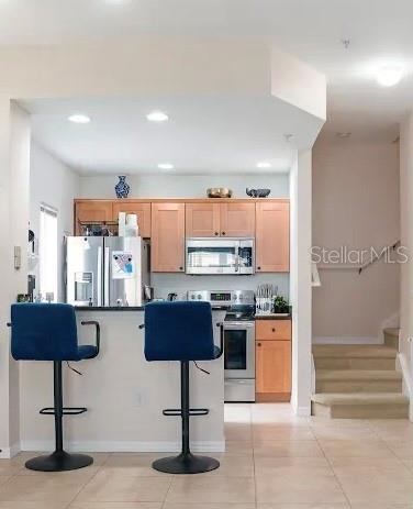 kitchen featuring a breakfast bar, light tile patterned floors, and stainless steel appliances