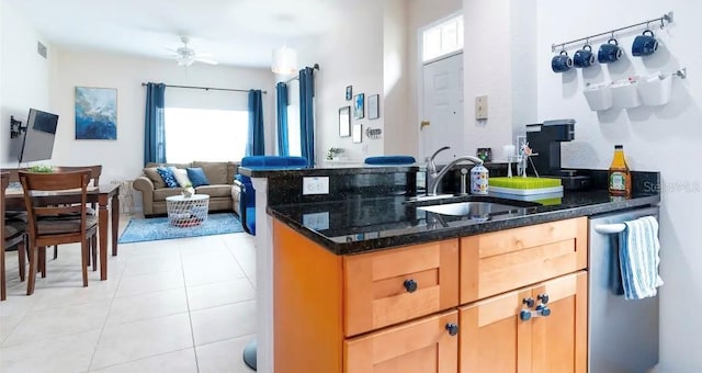 kitchen with ceiling fan, sink, light tile patterned flooring, and dark stone counters