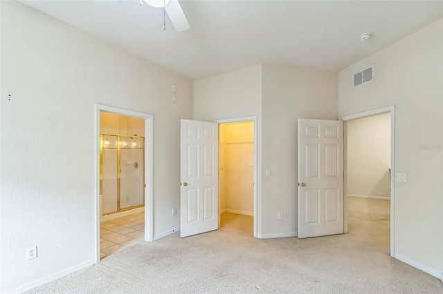 unfurnished bedroom featuring ceiling fan, light carpet, a walk in closet, and a closet