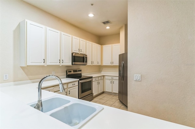 kitchen featuring appliances with stainless steel finishes, sink, light tile patterned floors, and white cabinets