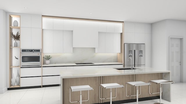 kitchen with white cabinetry, appliances with stainless steel finishes, a kitchen bar, and a kitchen island with sink