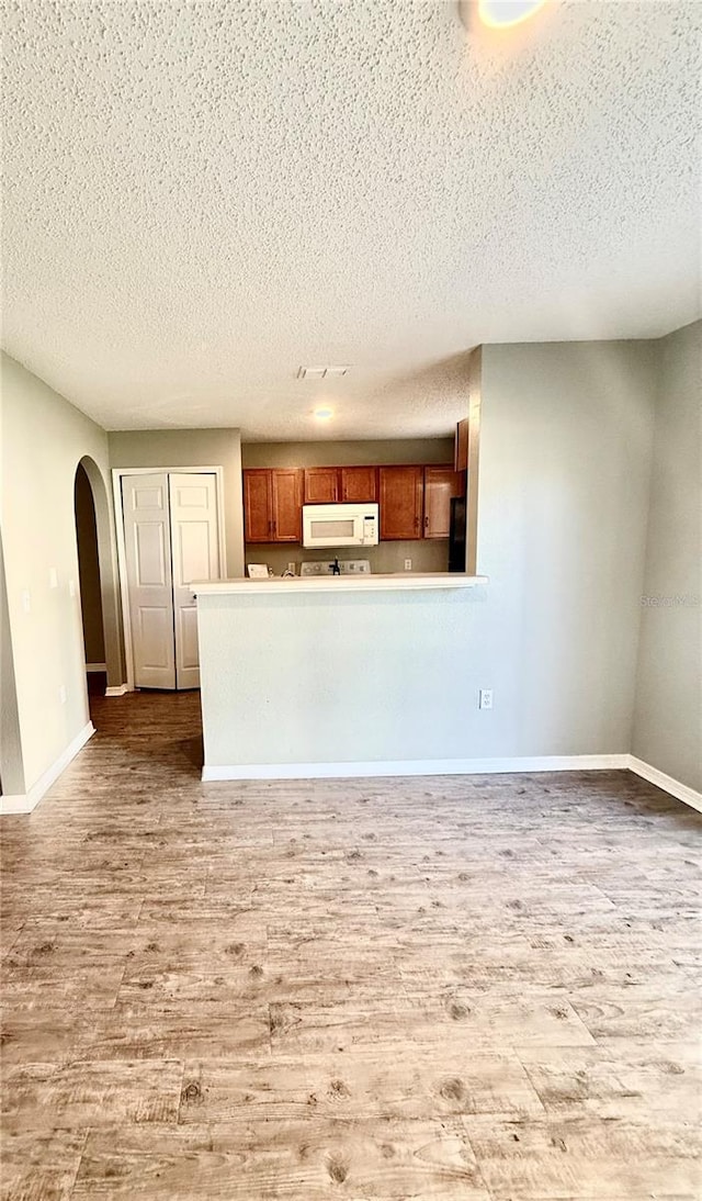 unfurnished living room featuring a textured ceiling and hardwood / wood-style flooring