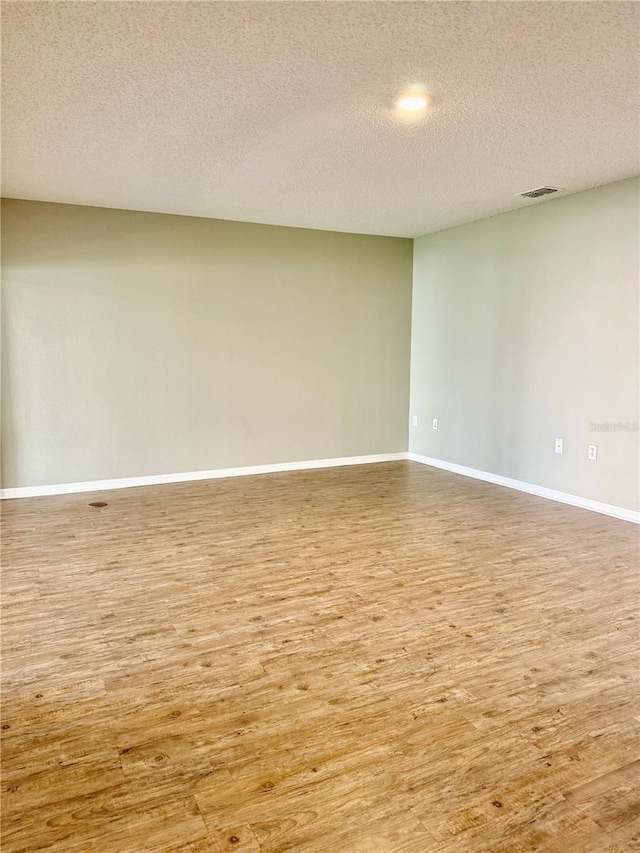 unfurnished room with a textured ceiling and hardwood / wood-style flooring