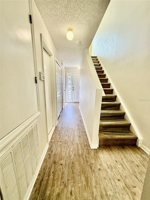 hall featuring a textured ceiling and light wood-type flooring