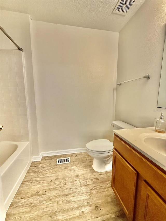 full bathroom featuring toilet, vanity, wood-type flooring, and washtub / shower combination