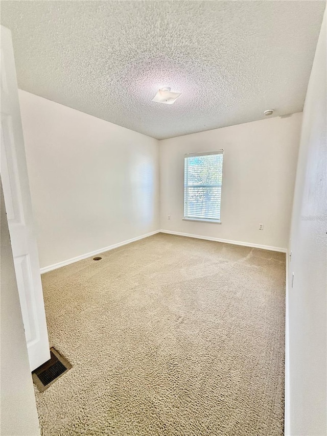 empty room with a textured ceiling and carpet flooring