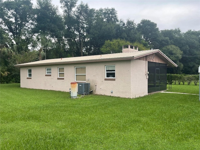 back of property with a lawn, a sunroom, and central AC unit