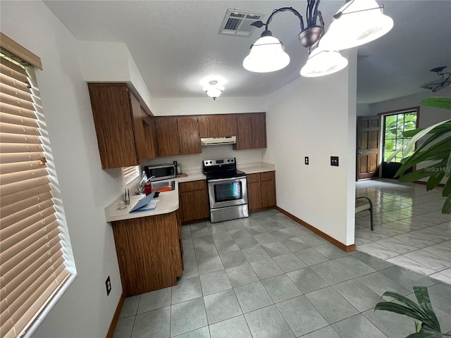 kitchen with stainless steel appliances, a chandelier, a textured ceiling, and exhaust hood