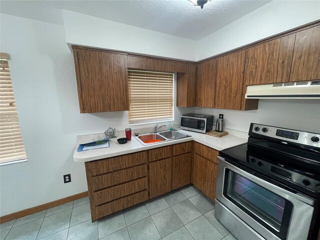 kitchen featuring a textured ceiling, sink, stainless steel appliances, light tile patterned floors, and extractor fan