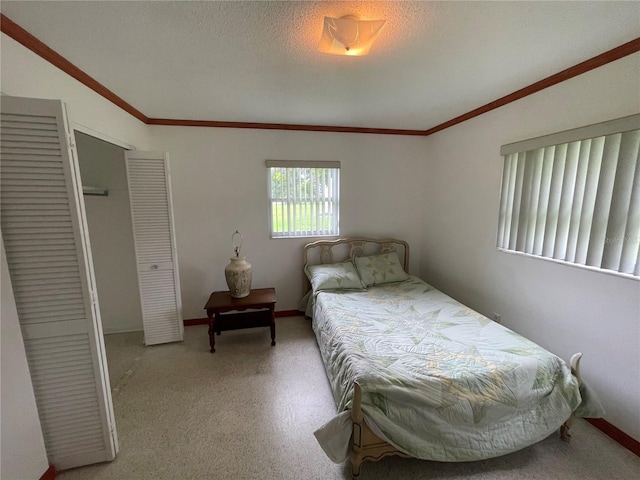 bedroom with light carpet, a closet, a textured ceiling, and ornamental molding