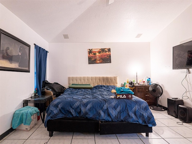 bedroom with lofted ceiling, light tile patterned flooring, and a textured ceiling