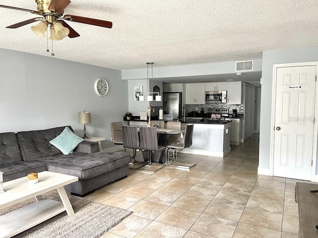 tiled living room featuring ceiling fan, sink, and a textured ceiling