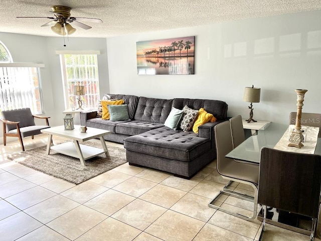 living room with ceiling fan, light tile patterned floors, and a textured ceiling