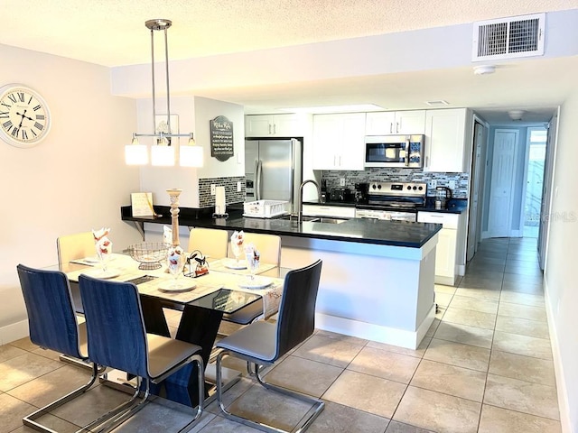 kitchen featuring sink, kitchen peninsula, decorative light fixtures, white cabinets, and appliances with stainless steel finishes