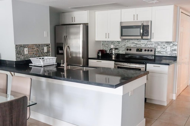 kitchen with light tile patterned floors, white cabinetry, appliances with stainless steel finishes, and tasteful backsplash