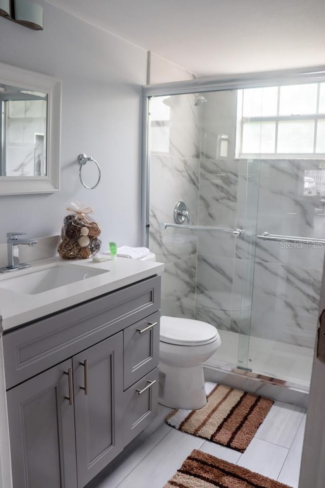 bathroom with tile patterned floors, vanity, toilet, and a shower with shower door