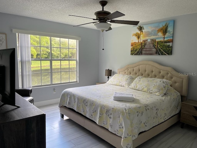 bedroom with ceiling fan, a textured ceiling, and multiple windows