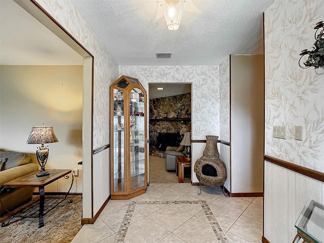 corridor featuring light tile patterned flooring and a textured ceiling