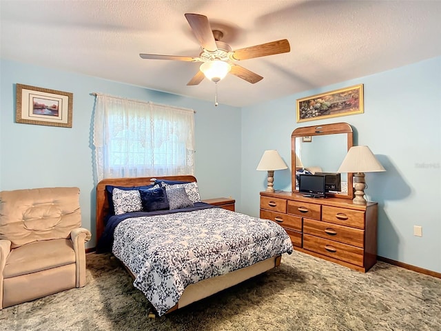 carpeted bedroom featuring ceiling fan and a textured ceiling