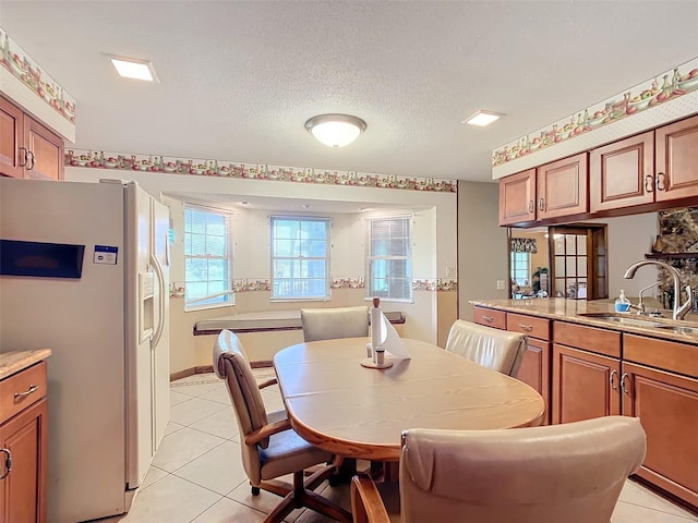 dining area with light tile patterned floors, a textured ceiling, and sink