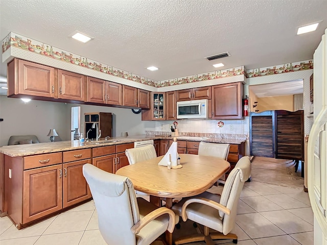 kitchen featuring kitchen peninsula, sink, light tile patterned floors, and a textured ceiling