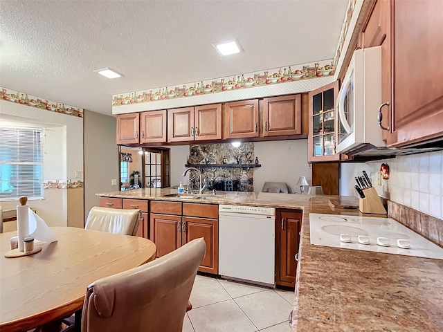 kitchen with white appliances, sink, light tile patterned floors, a textured ceiling, and kitchen peninsula