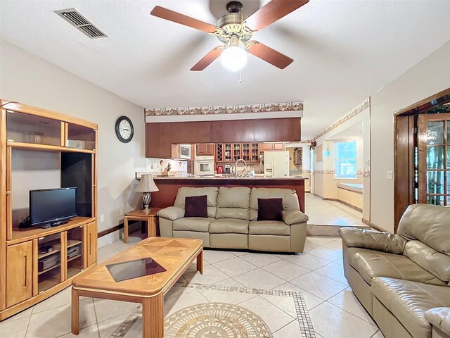 tiled living room with ceiling fan and sink