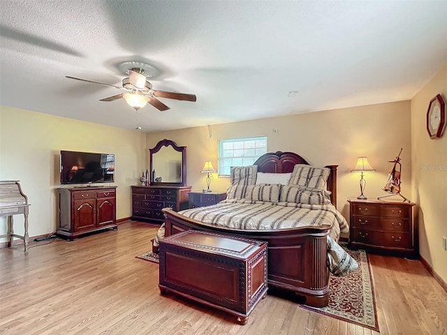 bedroom featuring ceiling fan, light hardwood / wood-style floors, and a textured ceiling