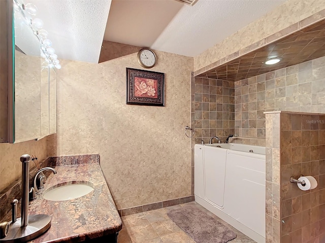 bathroom featuring vanity, a bathtub, and a textured ceiling