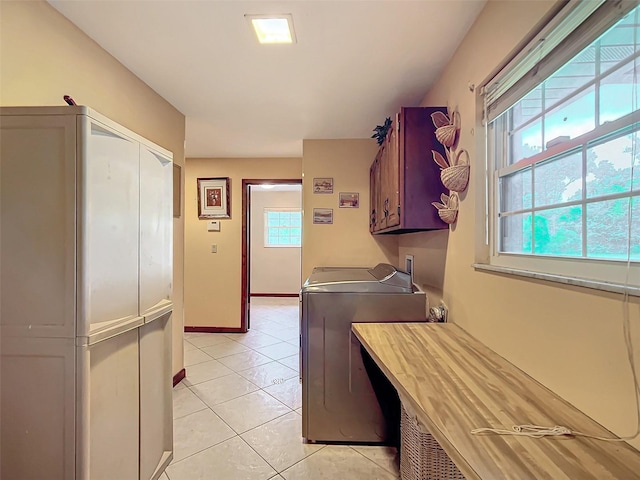 laundry area featuring washer and dryer, light tile patterned floors, and cabinets