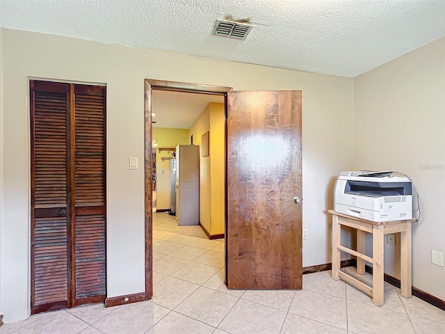 unfurnished bedroom with a closet, light tile patterned floors, and a textured ceiling