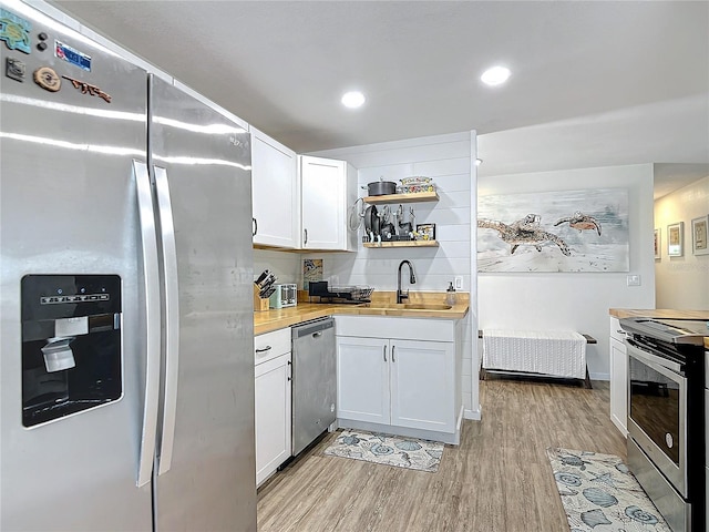 kitchen with white cabinets, sink, wooden counters, light hardwood / wood-style flooring, and stainless steel appliances