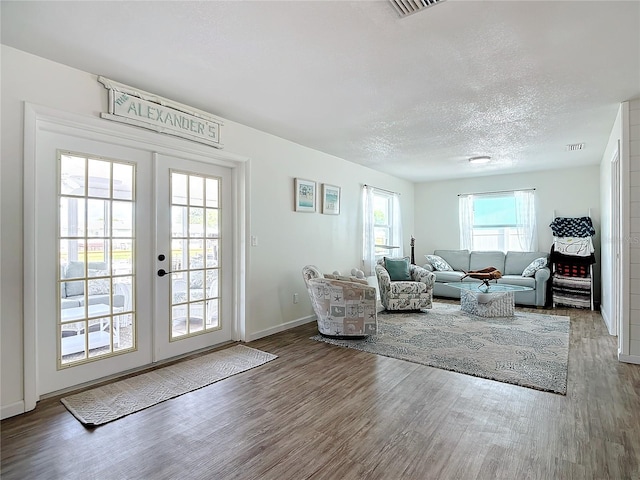 living room with wood-type flooring, a textured ceiling, and french doors