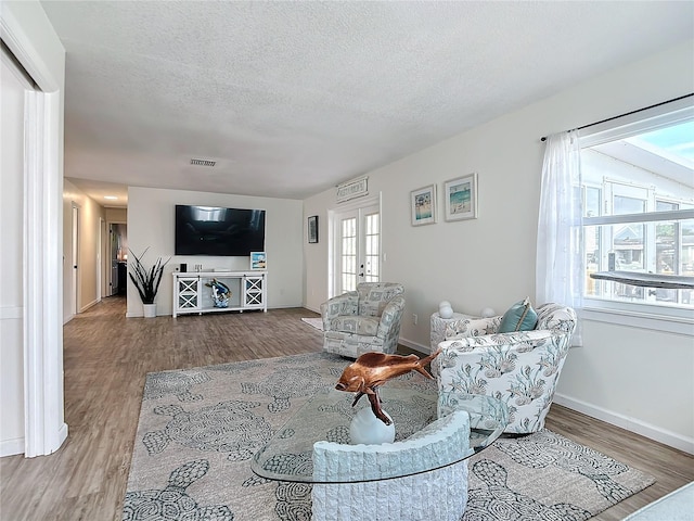 living room featuring a textured ceiling, hardwood / wood-style flooring, and french doors