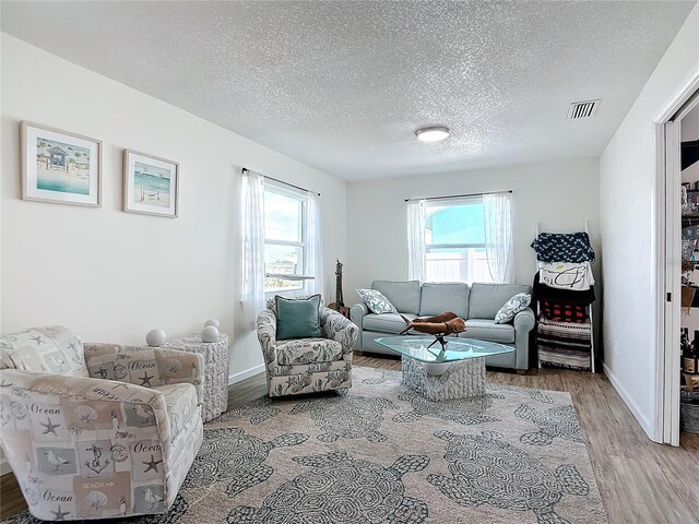 living room with a textured ceiling, a healthy amount of sunlight, and hardwood / wood-style floors