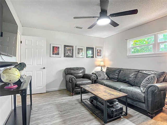 living room featuring light wood-type flooring, a textured ceiling, and ceiling fan