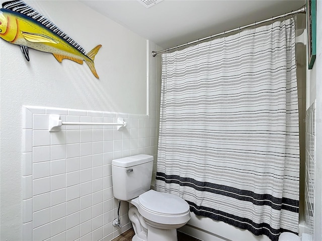 bathroom with shower / bath combination with curtain, tile walls, and toilet