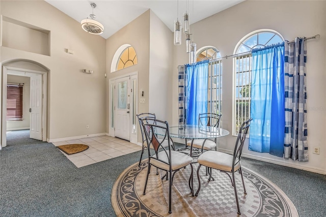 dining room featuring high vaulted ceiling and light colored carpet