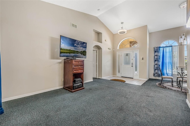 foyer entrance with light colored carpet and high vaulted ceiling