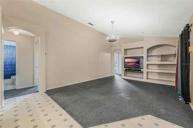 unfurnished living room featuring vaulted ceiling and built in features