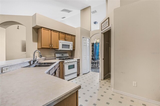 kitchen featuring white appliances, sink, and high vaulted ceiling